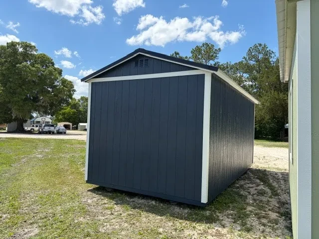 Exterior front right view of a dark blue side garden shed showing the wood door, windows and shutters