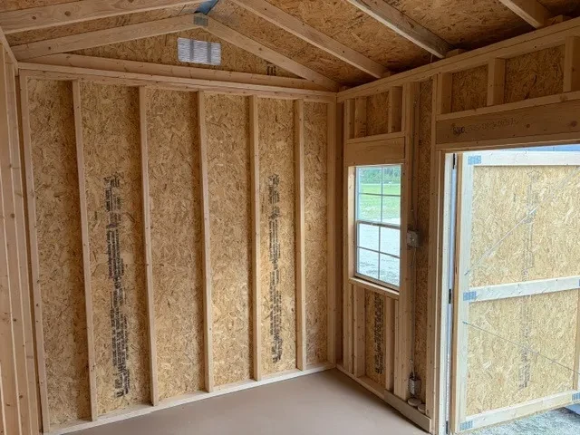 Interior of an 8x12 side garden shed showing a single wood door and one window