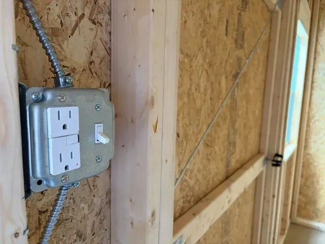 Interior of an 8x12 side garden shed showing a light switch and electrical outlet combo