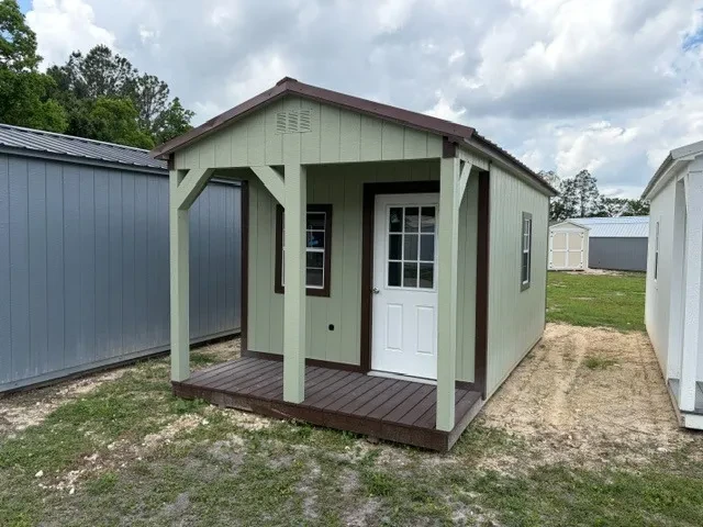 Outside of 10x20 cabin showing a front porch, entry door, windows, painted wood sides, and metal roof