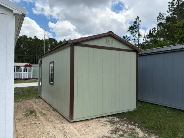 Back view of a 10x20 cabin with painted sage siding, dark brown trim, and brown metal roof