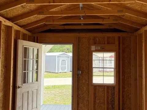 Interior of a 10x20 cabin showing the inside of the entry door, one window, and one light socket