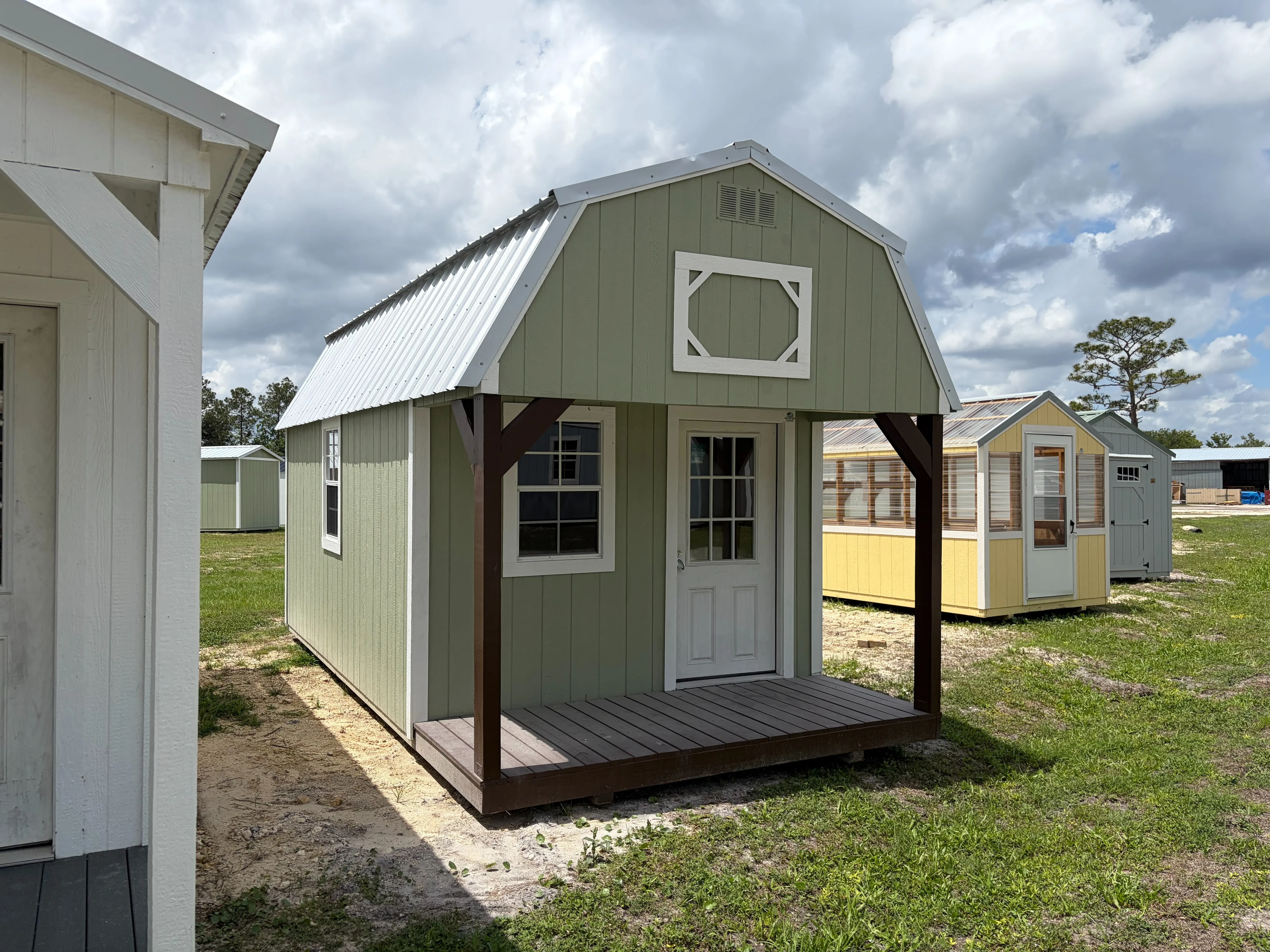 Outside of a 10x20 lofted barn cabin showing front porch, entry door, and two windows