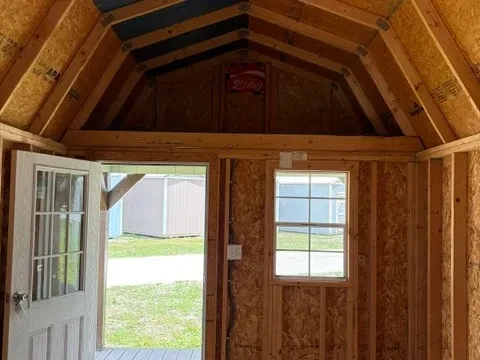Interior view of 10x20 lofted barn cabin showing entry door, one window, one light, and four foot loft above the porch