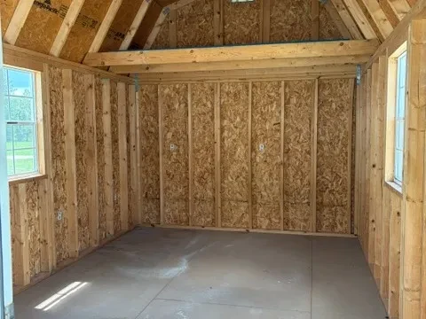 Interior view of 10x20 lofted barn cabin showing two windows and a four foot loft