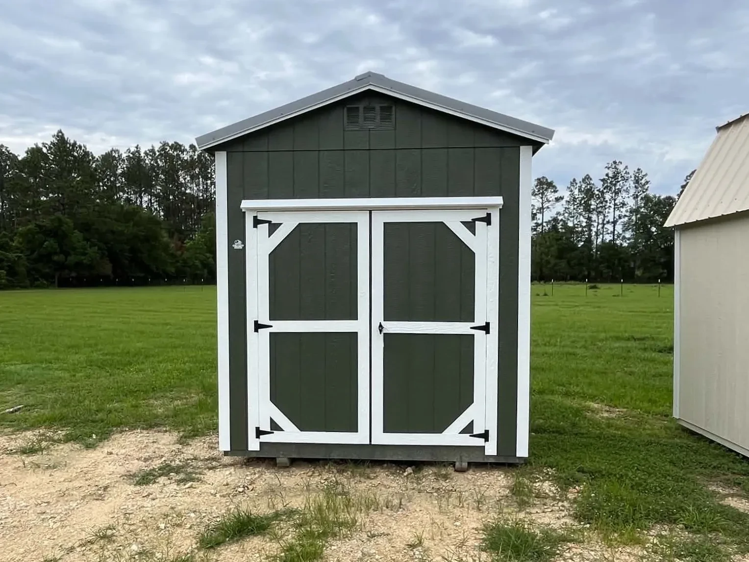 Exterior front view of a green 8x12 garden shed with wood door