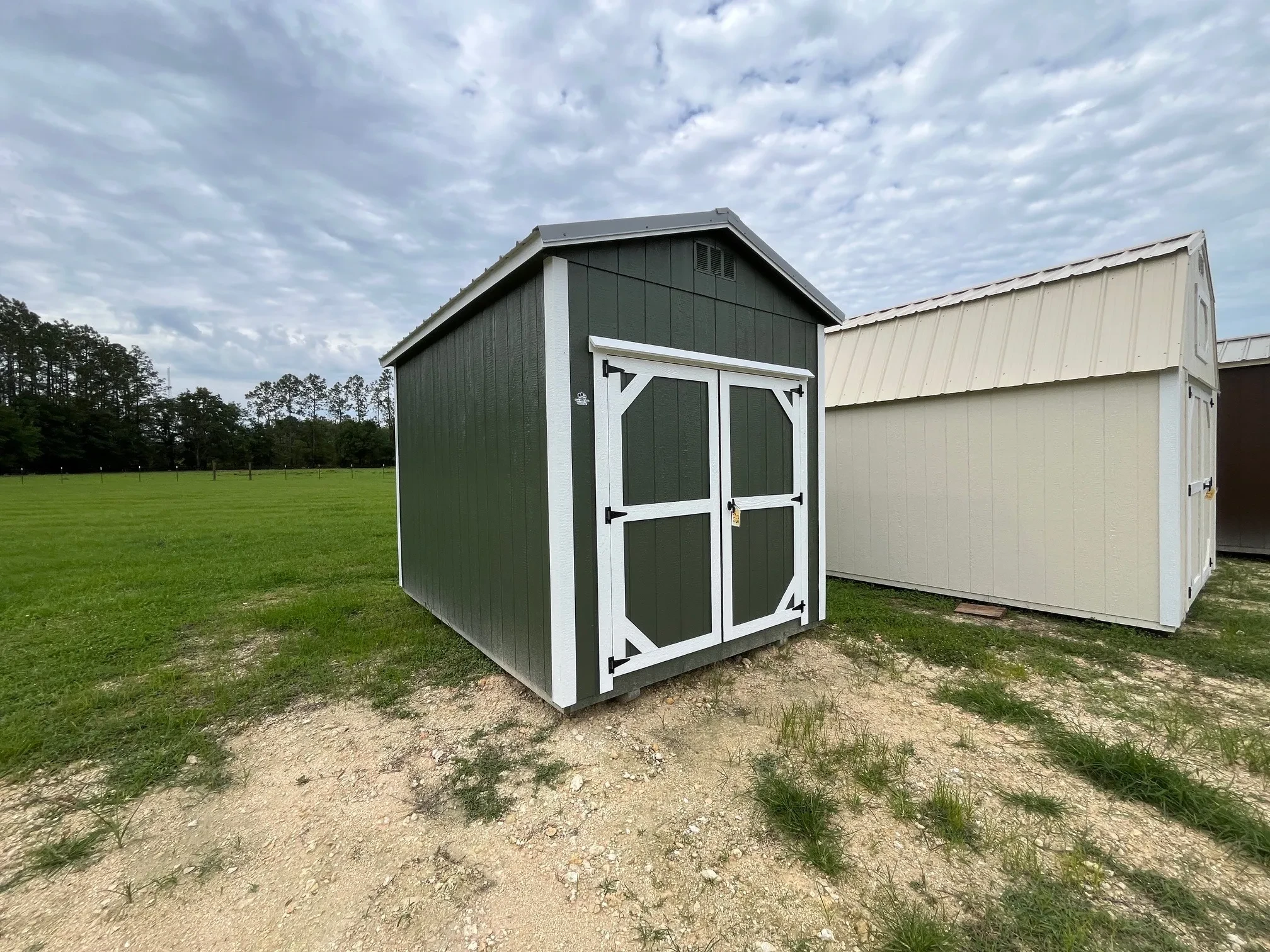 Exterior front left view of a green 8x12 garden shed with wood door