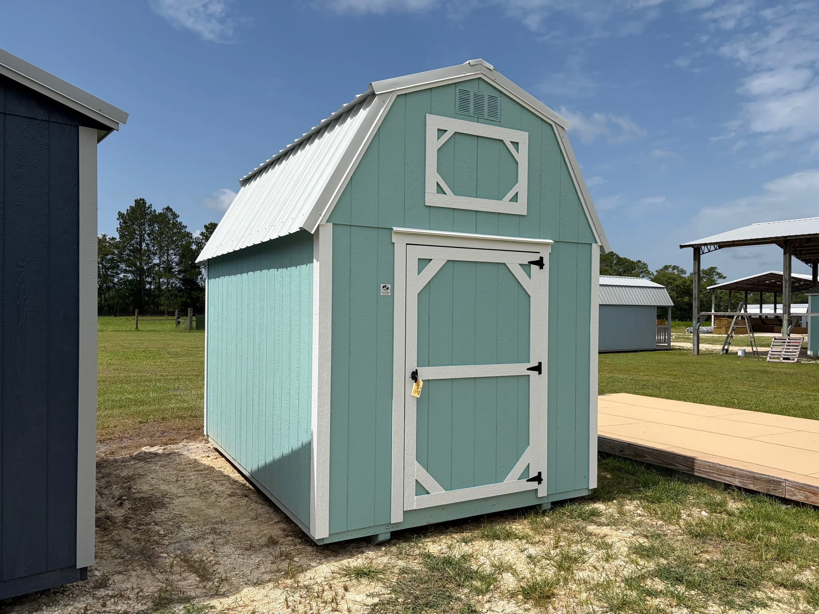 Exterior front view of aqua verde 8x12 lofted barn with a wood door