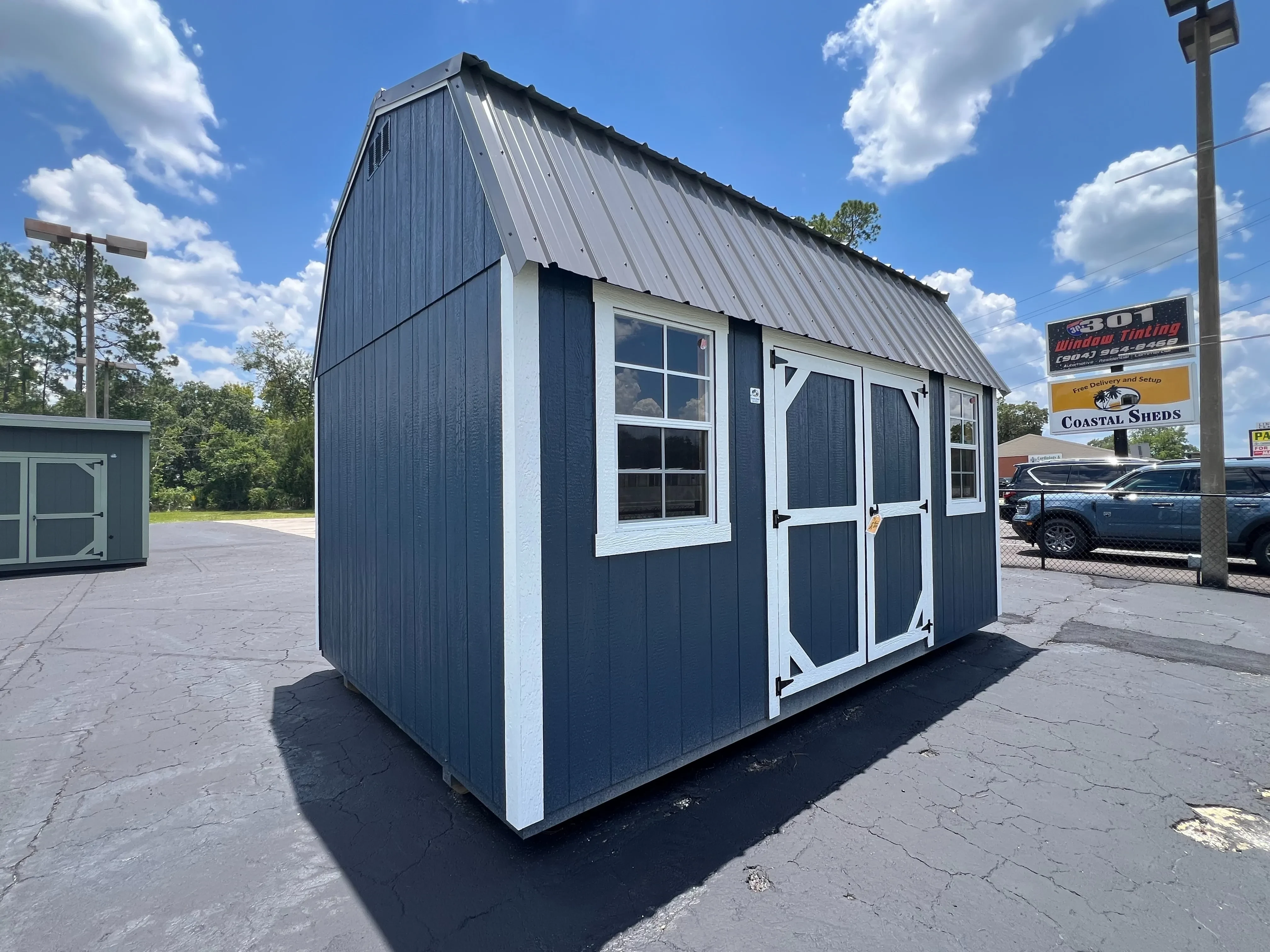 Outside of a 10x16 side lofted barn with double wood doors, two windows, painted wood side, and a metal roof.