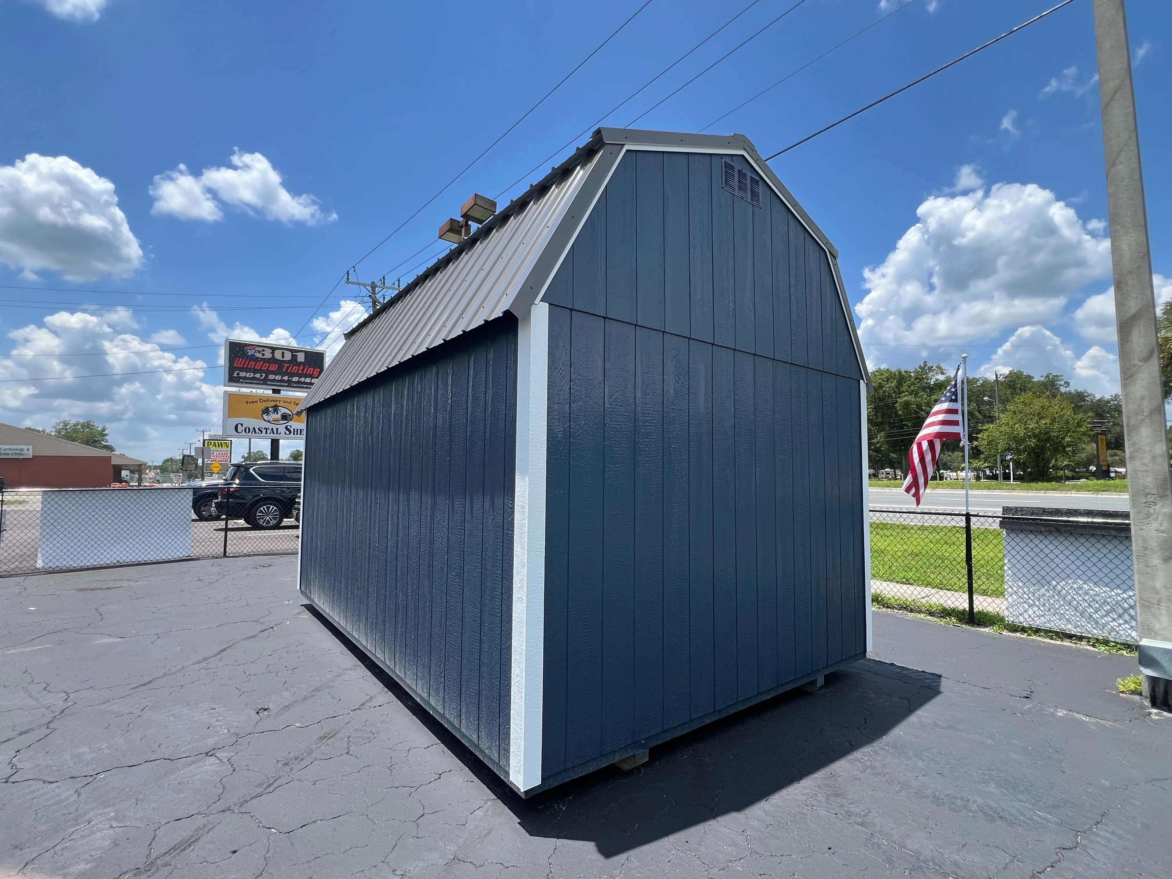 Back view of a 10x16 side lofted barn painted brook blue, with white trim, and a metal roof.