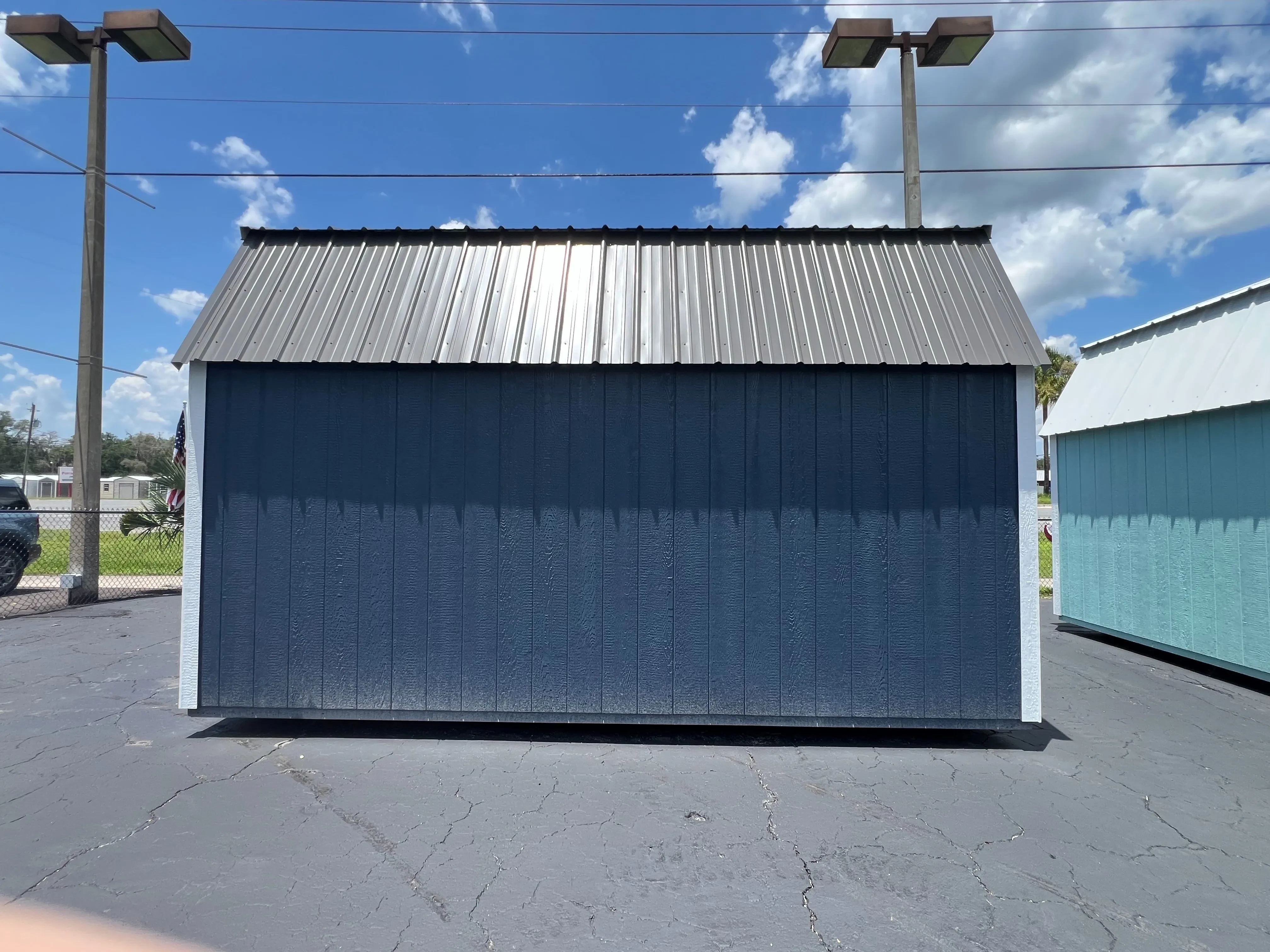 Back view of a 10x16 side lofted barn painted brook blue, with white trim and a metal roof.