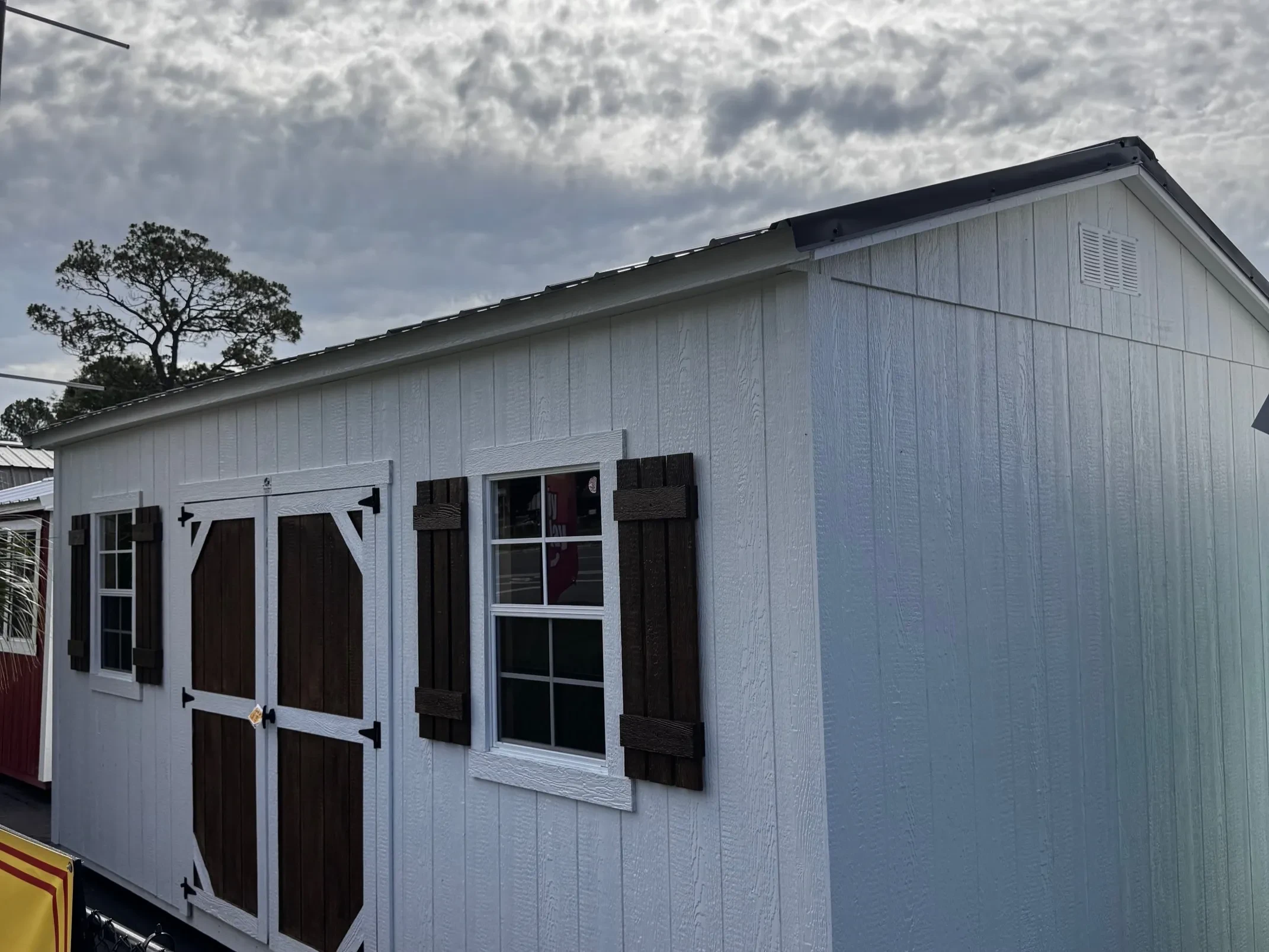 Exterior front right view of a white 10x20 side garden shed showing the wood door