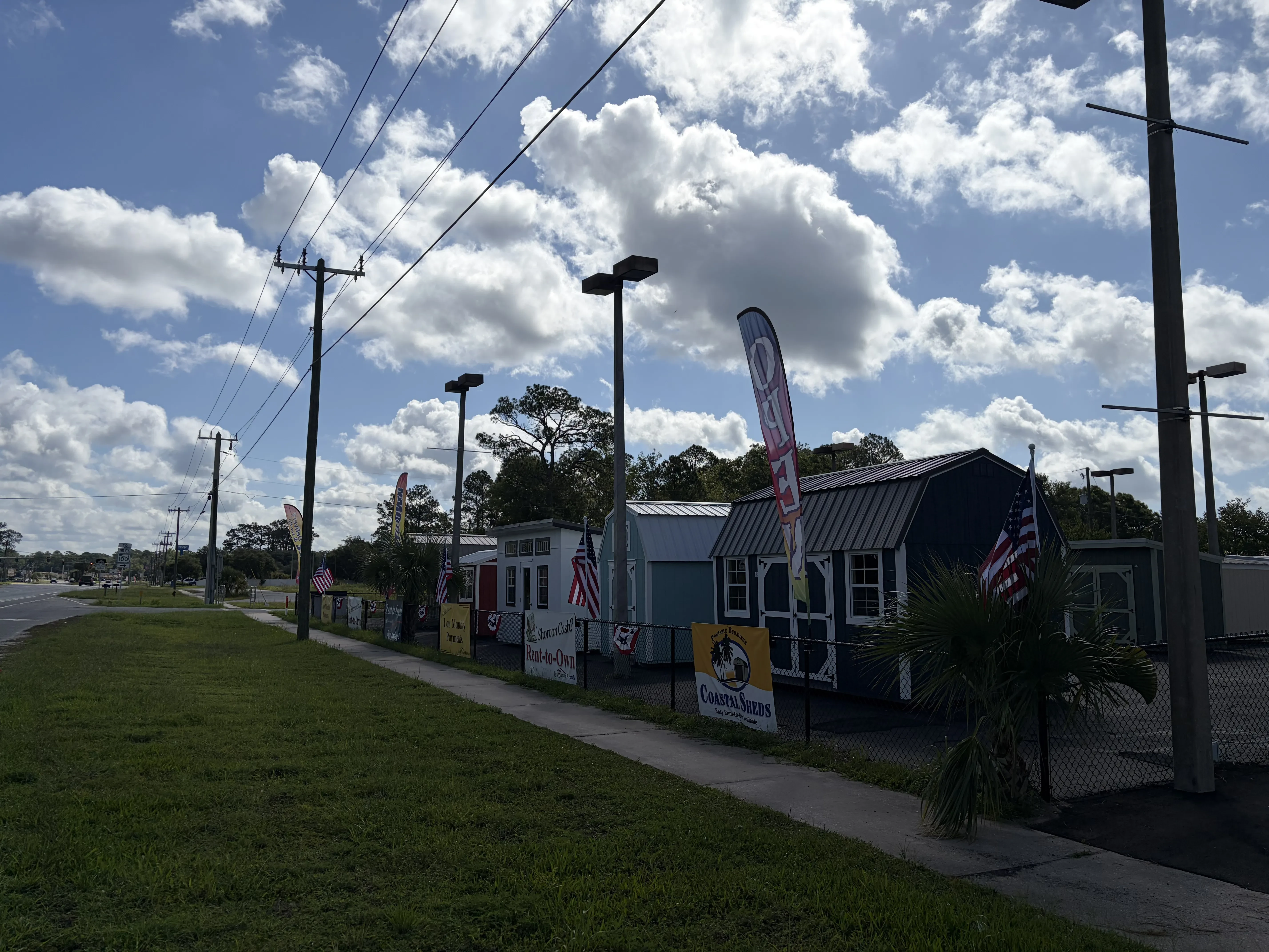 a picture from the street showing the shed lot with a row of sheds and colorful flags and banners