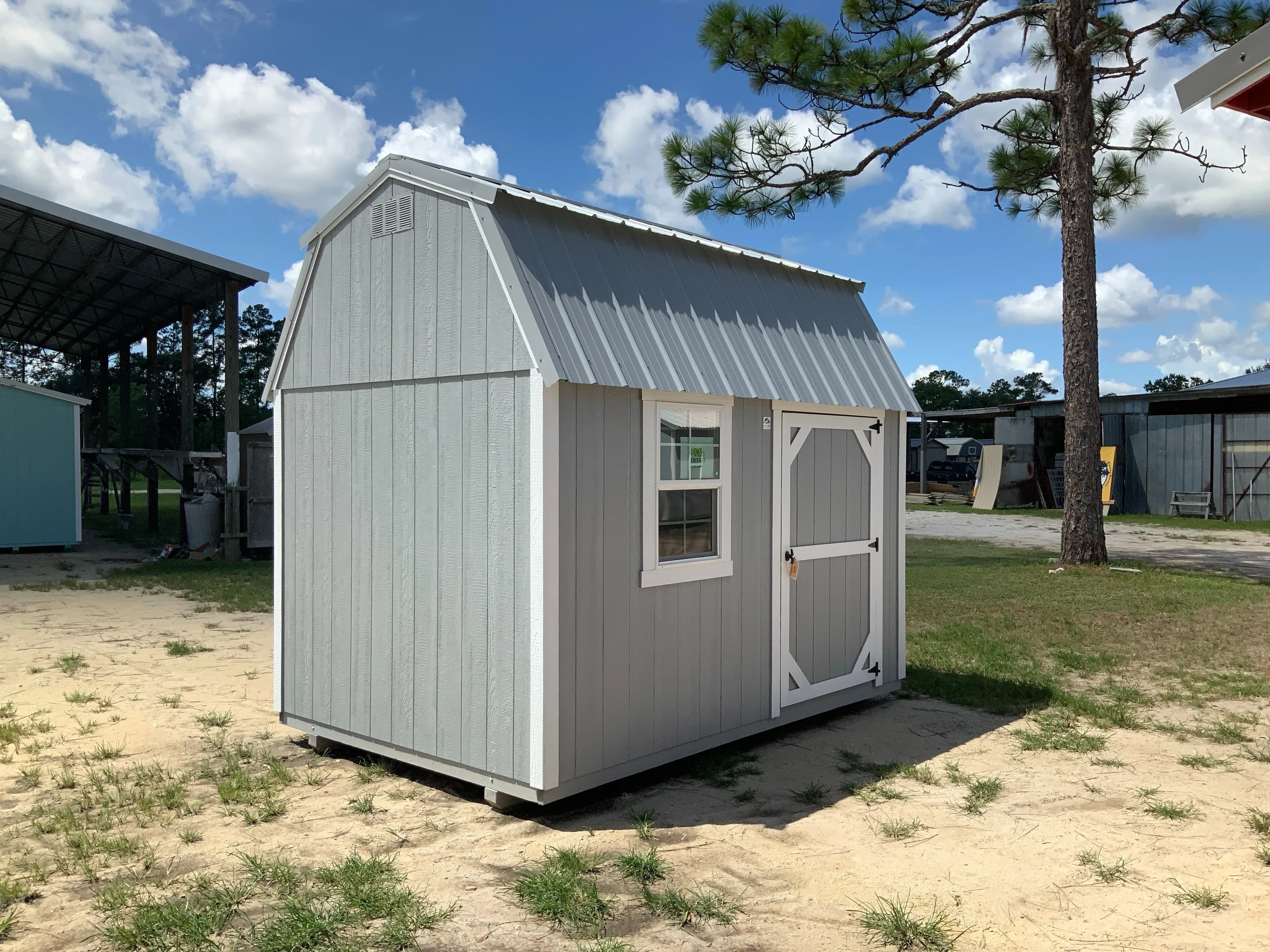 Exterior from left view of a grey 8x12 side lofted barn showing the door and window