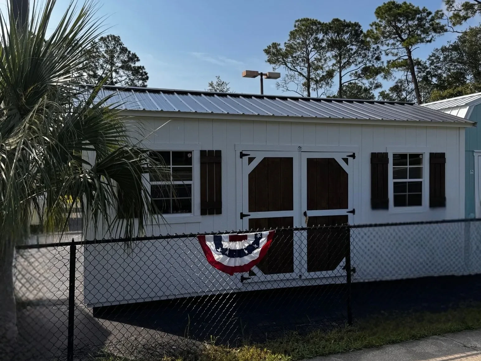 Exterior front view of a white 10x20 side garden shed showing the wood door