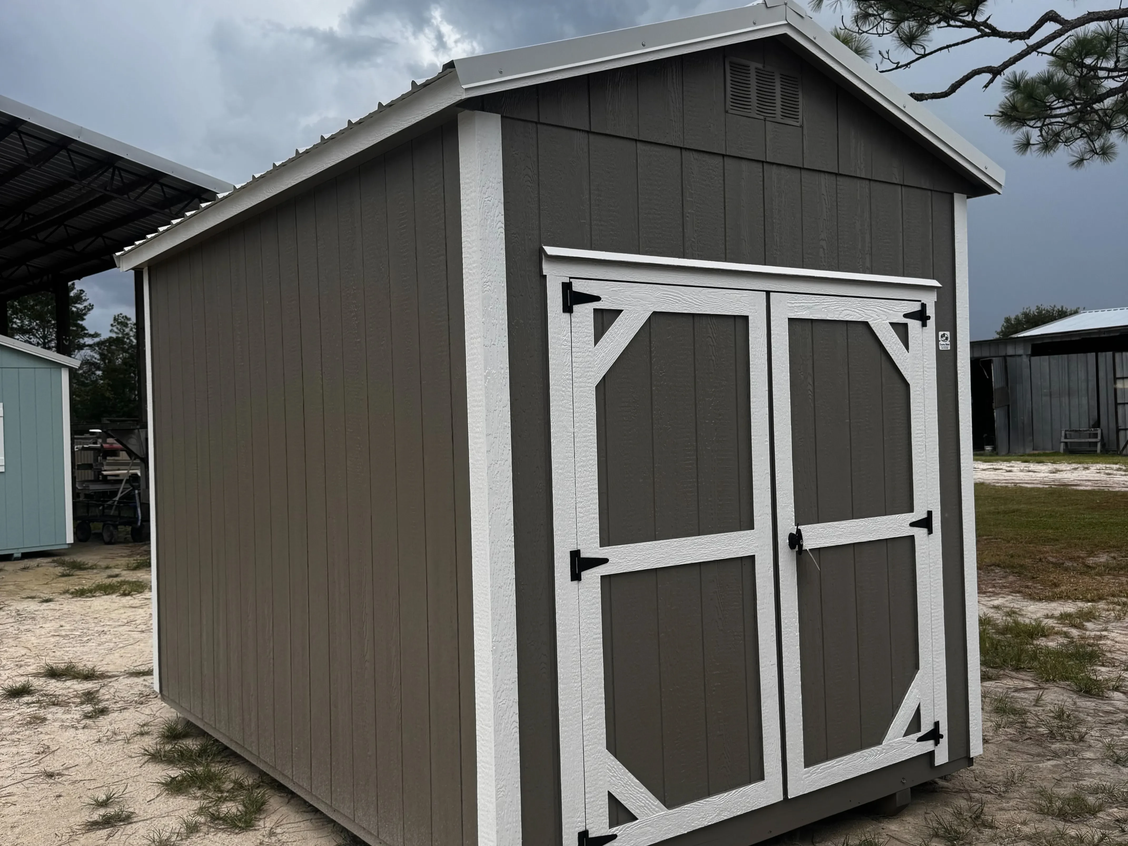 Exterior front view of a metal clay 8x12 garden shed with 6' double wood door