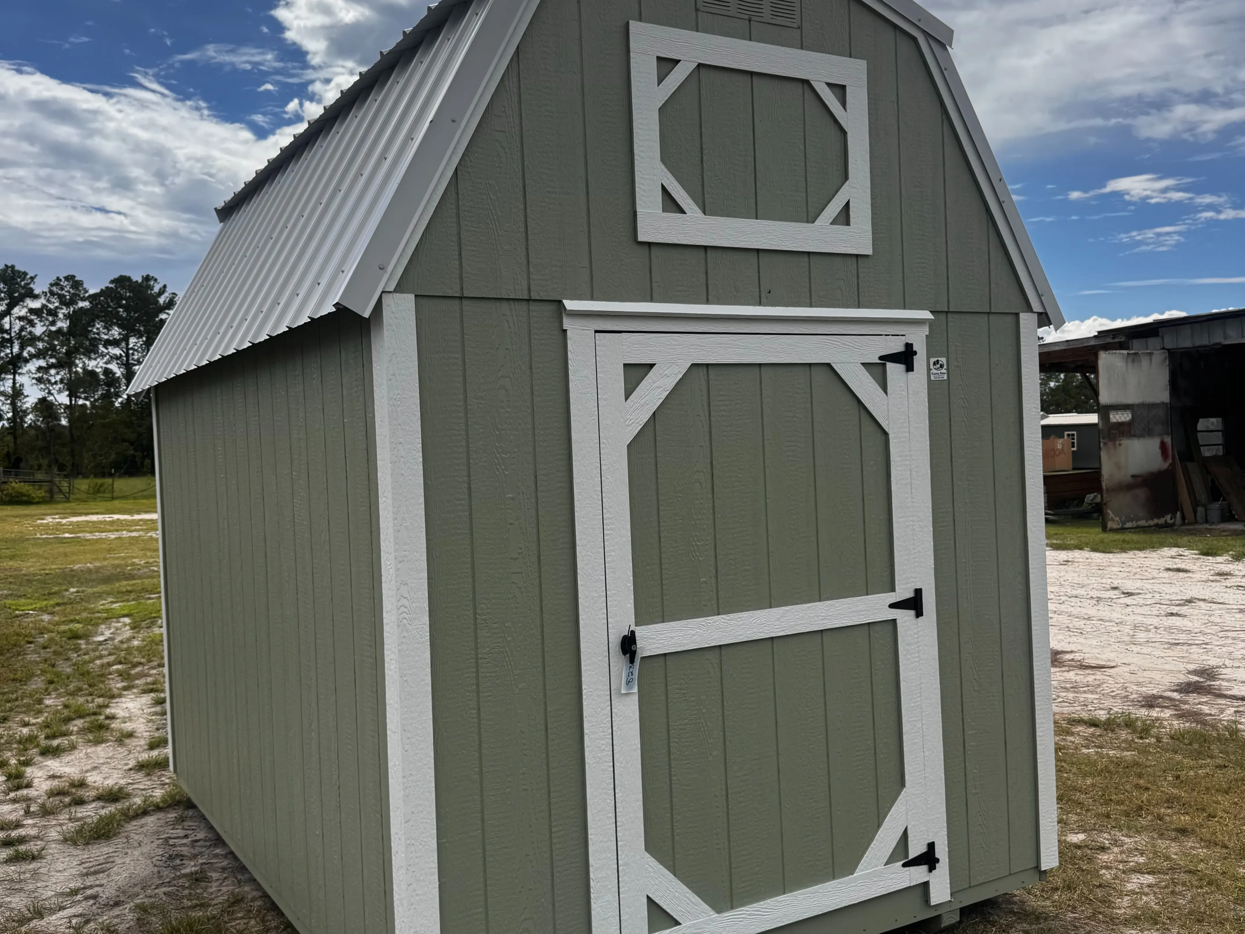 Exterior front right view of a sage 8x12 lofted barn showing a wood door