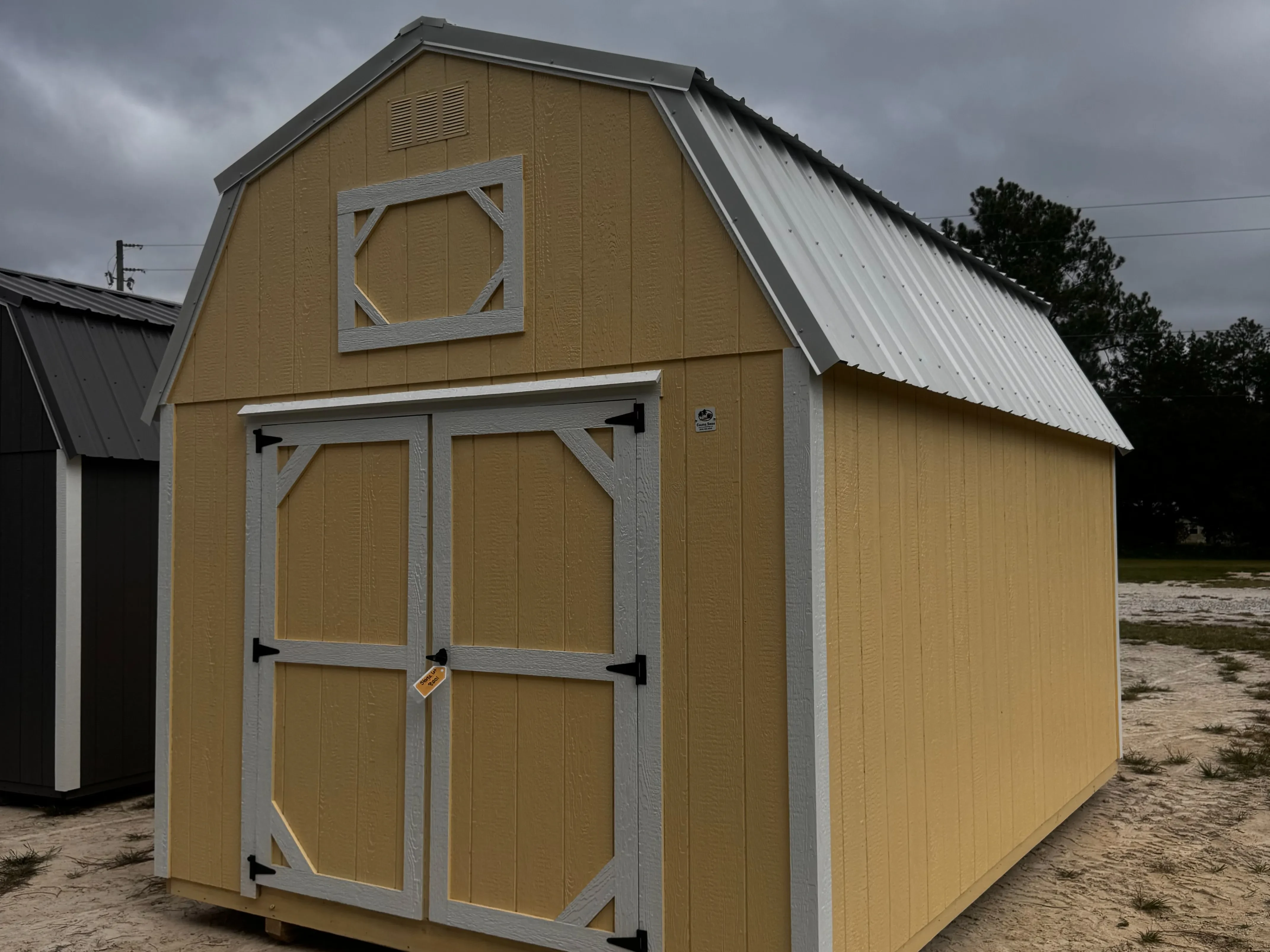 1Exterior front view of a Banana Cream 10x16 lofted barn with a wood door