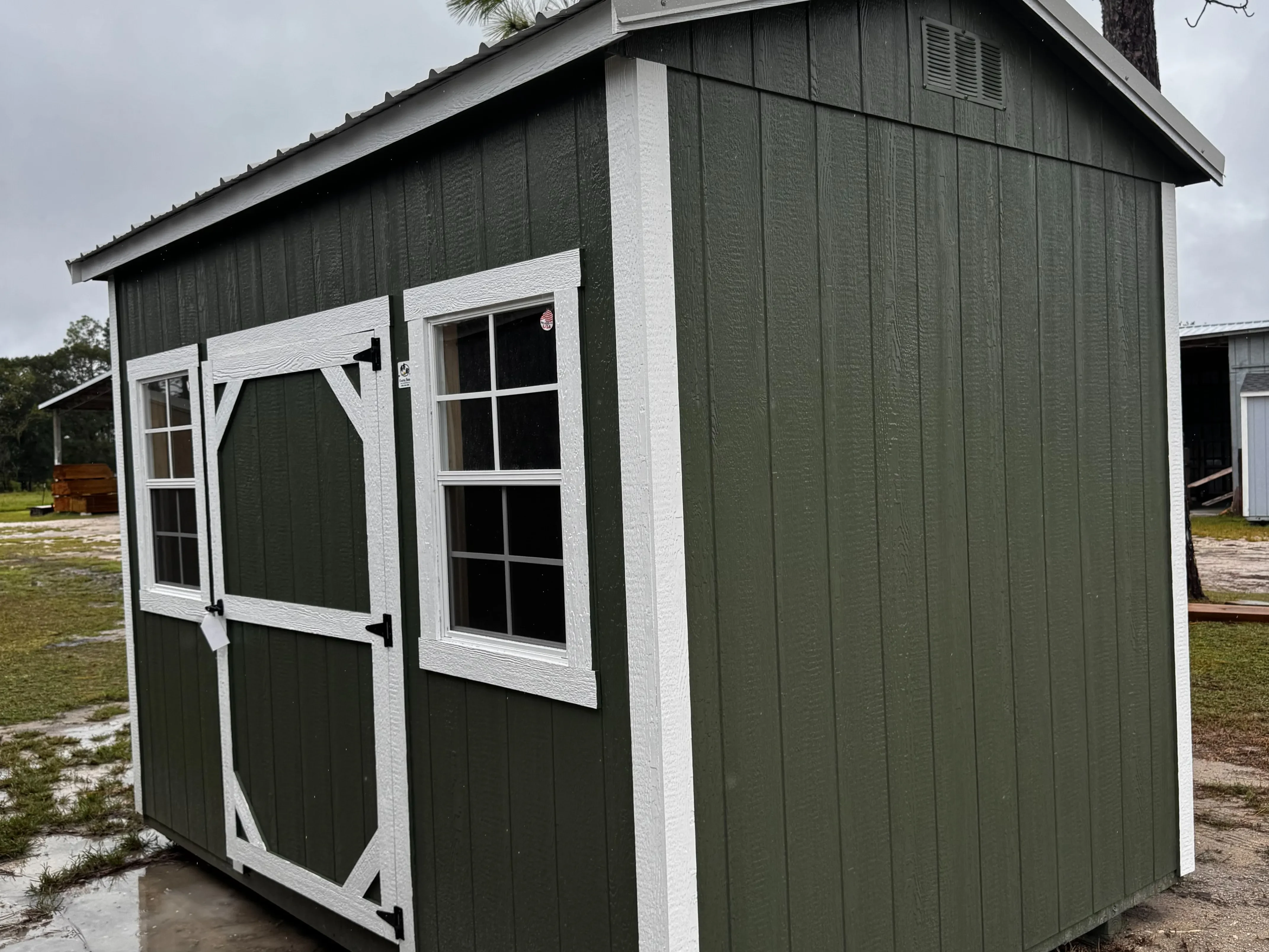 Exterior front of a garland green side garden shed with a single wood door and two windows