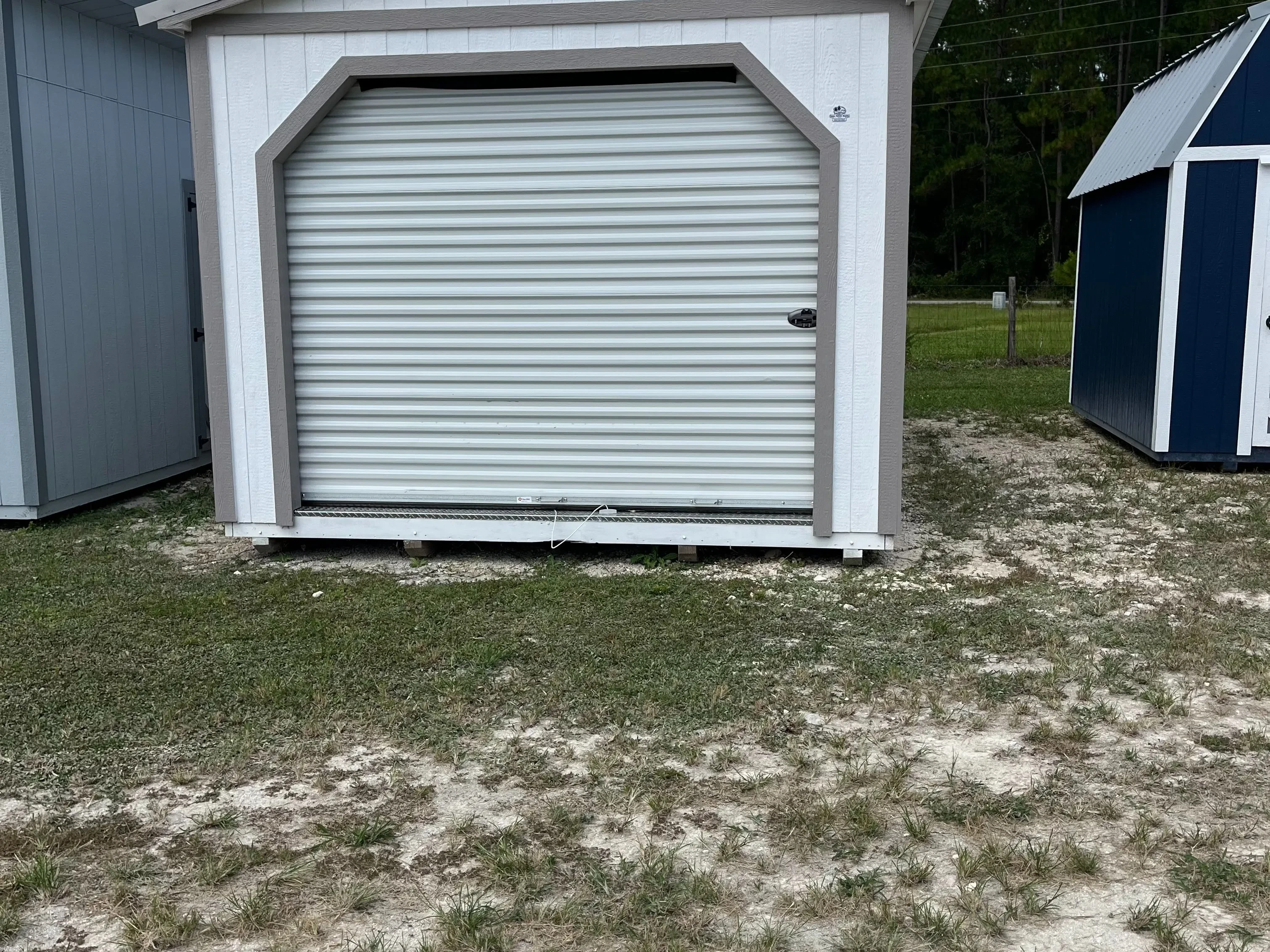 Exterior of white workshop shed showing a garage door in the end.